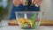 Closeup young woman adding greenery in bowl with salad in slow motion. Close-up tasty healthful dinner on table in