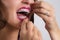 Closeup of young woman with braces flossing teeth