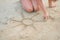 Closeup on young woman drawing on sand