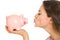 Closeup on young woman kissing piggy bank