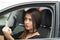 Closeup young woman sitting in car giving the finger angrily, as seen from outside drivers window, female driver concept