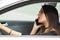 Closeup young woman sitting in car holding talking on mobile phone and coffee cup, as seen from outside drivers window