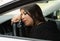 Closeup young woman sitting in car interacting tired and sleeping, as seen from outside drivers window, female driver