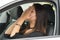 Closeup young woman sitting in car interacting upset frustrated, covering face in hands, as seen from outside drivers