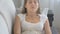 Closeup of young woman suffering from allergy sitting on sofa and sneezing in paper tissue