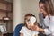 Closing left eye. Little girl tries new blue glasses in ophthalmologic office with female doctor