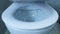 Closing toilet lid, close up view. Front view of white toilet with lid. Automatic toilet lid