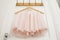 Clothes hanger with pink girl tutu dress isolated on the white door. Fashion, baby clothes.