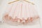 Clothes hanger with pink girl tutu dress isolated on the white door. Fashion, baby clothes.