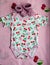 Clothes for newborns with cherries and baby`s pink bootees on the bedclothes with cherries