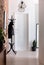 Clothes on rack in white minimal anteroom with lamps and plant next to door