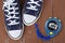 Clothes shoes and sport - top view fragment pair blue gumshoes and Stopwatch wooden background