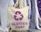 Clothes swap reusable bag with recycle textiles symbol in front of rack of clothes. Recycle clothes for sustainable living