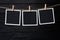 Clothespins with empty instant frames on twine against black wooden background. Space for text