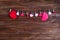 Clothespins with red hearts on a ribbon as a border on a brown wooden background with space for text. The concept of