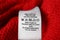 Clothing label with care symbols and material content on red sweater, closeup