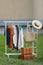 Clothing rack with different garments in yard. Garage sale