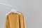 Clothing rack with stylish autumn outfit. Yellow, mustard color linen jacket, shirt and pajamas trousers dress on