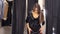 Clothing, wardrobe, fashion, style and people concept - happy brunette woman with black dress on hanger at the mirror at