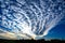 Cloud band in blue sky. Rippled altocumulus clouds spreading out. Cloud pattern on cloud band in blue sky