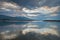 Cloud reflections in a water of aegean sea at sunrise, Volos harbor with Pelion mountain in background