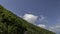 A cloud swirls over the edge of the mountain. Timelapse.