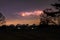 Cloud to cloud lightning illuminating the sky over a flat open park.