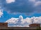 Cloud - towering cumulus - forming in the distance above the roof of the house