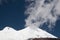 Cloud and two tops of Elbrus volcano with glaciers and blue sky in sunny day.