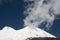 Cloud and two tops of Elbrus volcano with glaciers and blue sky in sunny day.