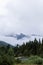 Clouded mountains behind an overgrown barn hiding in a Forrest