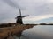 Clouded skies over countryside road and windmill, Holland