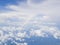 Clouds from airplane window with blue sky and high angle ground