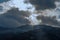 The clouds break up over snow-covered, forested hills