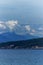 Clouds, coastal mountains, snow, water and greenery viewed from the Thick white clouds drift over the mountain on the Pacific