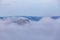 Clouds covering forested hills.