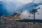 Clouds enveloping modern ropeway with benches in amazing mountainous terrain.