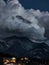 Clouds floating over mountain alpine peaks in the late evening, an atmosphere of darkness and beauty