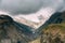 Clouds fly low over rocks. Mountain peaks covered with snow. Var