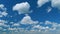 Clouds formation running across the blue sky. White puffy and fluffy layered clouds on blue sky. Time lapse.