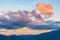 Clouds glowing in orange sunset light over mountains.