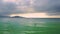 Clouds hang above ocean and girl figure on paddleboard