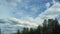 Clouds moving in layers in different directions above the forest. Time lapse clouds. Cloud running across the blue sky