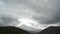 Clouds moving over majestic mountain peak with snow patches timelapse