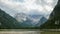 Clouds are Moving over the Peaks of the Alpine Mountains and a mountain lake. Time Lapse