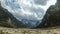 Clouds are Moving over the Peaks of the Alpine Mountains and a mountain lake. TimeLapse