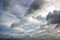 The clouds are multicolored, thunderous bizarre shapes against the blue sky and the sun above the ocean surface.