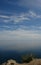 The clouds over the calm water of Baikal Lake on a clear summer day, view from the rocky shore of Cape Khoboy (Siberia,