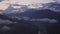 Clouds over city in mountain valley from drone above. Aerial takeoff view