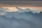 Clouds and peaks rise above jagged blue ridges in Julian Alps